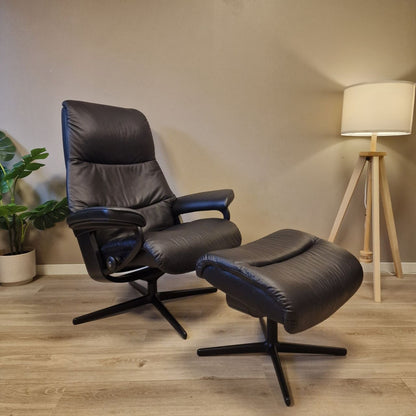 Stressless View (M) i svart skinn sett på skrå, med krakken foran stolen