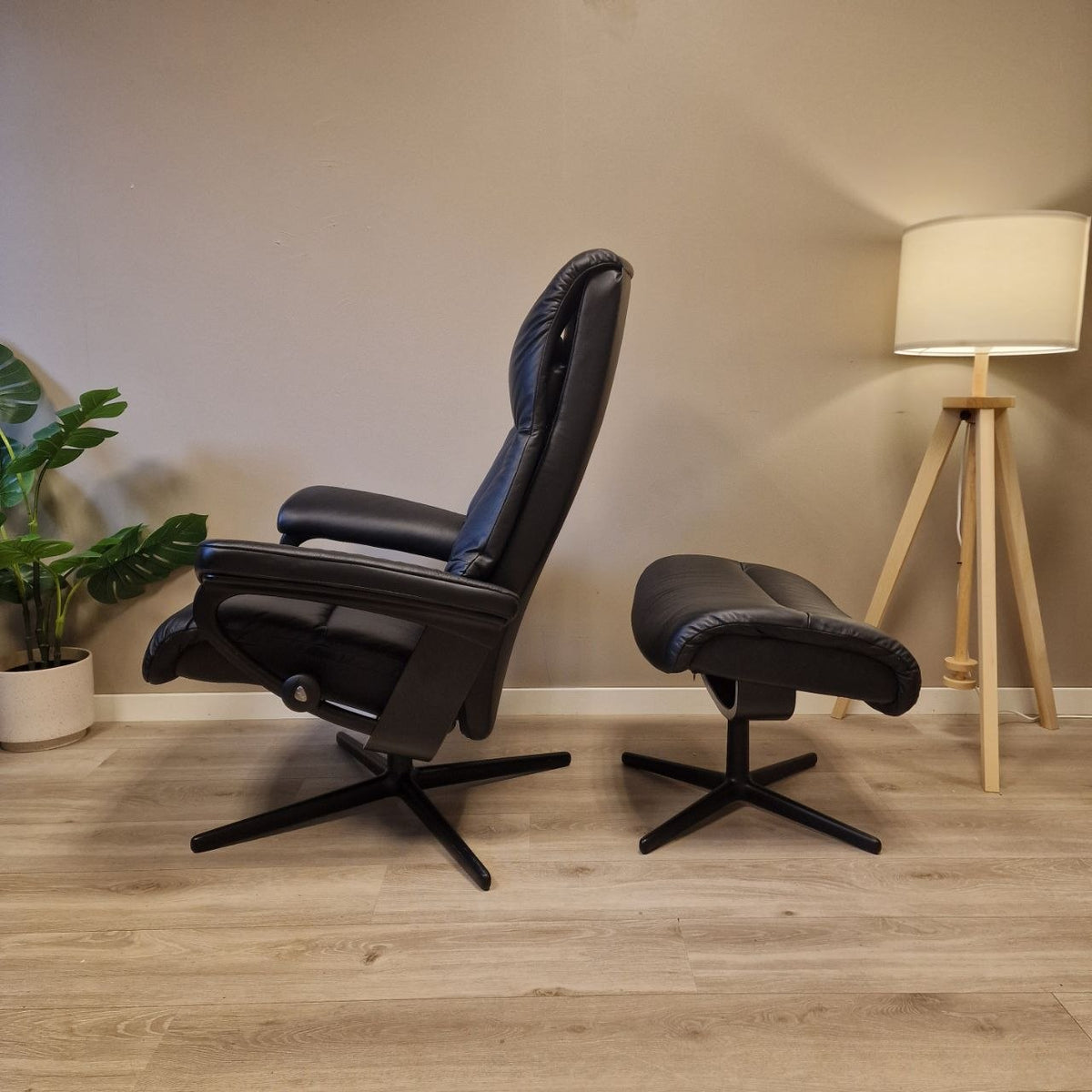 Stressless View lenestol i svart skinn sett fra siden i oppreist sittestilling, med krakk